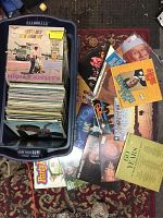 Two large plastic bins filled with vinyl records, records are stacked vertically and a selection of records is displayed on the floor around the bins to show variety and condition.