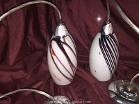 Pair of modern art glass drop pendant lights with abstract swirl patterns in white, black, and brown.