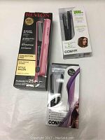 Three hair straighteners in original packaging: one Revlon Collection Pro in pink, two Conair travel models in black and purple.