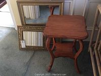 Photo showing two gold-framed mirrors leaning against a wall with the pine fern table in front.