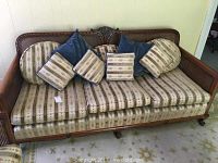 Full front view of the 3 seat sofa showcasing the cane back and arms with patterned upholstery cushions and various throw pillows.