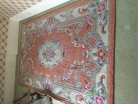 Full view of the salmon colored rectangular area rug with floral raised design and beige carpet underneath