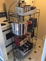 Photo of black metal bakers rack placed in kitchen showing its design, three shelves, and dimensions