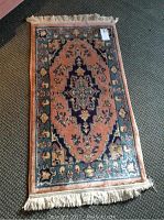 Full view of the small rectangular area rug showing its central medallion design and fringe edges