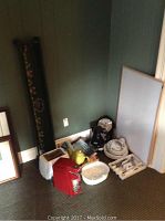 Photo of various kitchen items including toaster, red espresso machine, kettle, ceramic teapot, knives, and dishes on floor corner.
