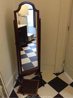 Full view of the cheval mirror standing on a black and white checkered floor, showing its height and frame design.