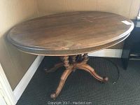 Full view of the oval wooden parlour table showing surface wear.