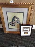 Photo showing both framed items leaning against a wall, the larger Croft watercolour and smaller stamp collection frame.