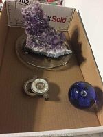 Box overview showing amethyst geode, blue glass paperweight and folding magnifier