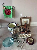 View of entire lot including planter, glass bowl, lantern, framed print, barometer, bowls, decorative flag, and assorted small items on floor.