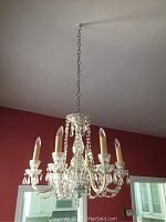 Full view of the glass chandelier hanging from the ceiling, showing six candle-style lamps and the chrome chain.