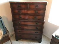Front view of tall antique style chest showing 8 drawers with ornate oval drawer pulls and finished wood surface.