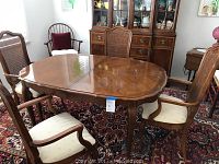 Full view of the Thomasville dining table with four chairs around it, showing wood grain and chair design.