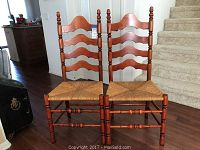 Two cherrywood ladder back chairs placed side by side on a wood floor, showing front and backrest details