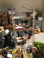 Full view of vintage iron bakers rack with various small items on shelves and surrounding it