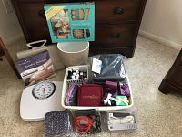 Wide view of all items including scale, hair dryer, essential oils in basket, home spa set, and boxed small gifts.
