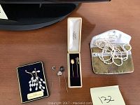 Pair of pearl earrings and three loose hat pins on tabletop