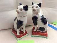 Front view showing the two Staffordshire cat figurines sitting side by side, details of spotted pattern and facial features.