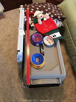 Large plastic dog kennel with metal front door, ceramic pet bowls on top, blankets and pet gate beside it.