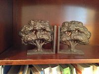 Two tree-shaped metal bookends displayed on a wood shelf.