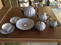 Two lidded porcelain pots, sugar bowl, creamer, large bowl, single cup on saucer and extra saucer displayed on table