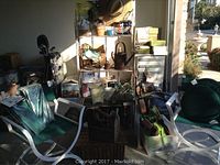 Photo showing two green folding director chairs with white frames, seat cushions, and garden-related items on shelves behind.