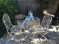 Overall view of folding metal patio table with two matching chairs and decorative items on the table.