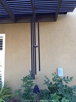 Long rod iron wind chime hanging outdoors with multiple tubular chimes and black clapper