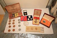 Overview of assorted commemorative coins, medallions, and display boxes including Chinese coin with glass chop, Western Samoa coins, and Ken Griffey Jr. medallion.