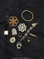Close-up of selected costume jewelry pieces including watches, pins and bracelets on black background