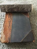 Top view of black plastic-wrapped bundle labeled '1890 MARS' and half-leather bound atlas on carpet