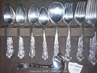 Multiple spoons and forks in brown lined storage tray with anti-tarnish compartments.