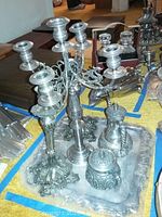 Photo shows five-arm silver plate candelabra, two silver candlesticks with floral pattern, teapot and lidded sugar bowl on a silver tray.
