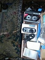 Two Walkman units stacked with charger cable and plastic case at right