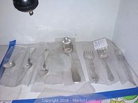 All eight pieces in plastic sleeves: four small spoons, serving spoon, ladle and two forks