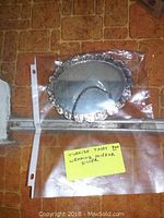 Oval Turkish wedding mirror in 900 silver inside plastic sleeve with yellow tag describing it.