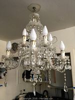 Front and side views of the pressed glass chandelier showing candle bulb sockets, clear glass arms, and hanging prisms.