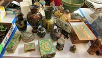 Group of Asian pots, vases, various decorative boxes including turquoise and enamel boxes, brass items laid out on table.