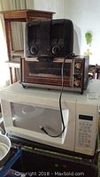 Stacked kitchen appliances from top to bottom: black Hamilton Beach toaster, GE toaster oven, white GE microwave.