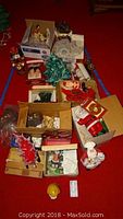 Top-down view of multiple boxed holiday ceramic figurines including Santa, Christmas trees, and other festive items.