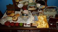 Wide view of assorted trinket boxes, trays, glasses, grooming kit and mirror on table
