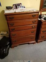 Photo of cherry wood four-drawer chest of drawers with metal handles, showing overall condition and size.