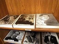 Six framed black and white signed celebrity photos placed on a wooden shelf, showing Jane Powell, Barbara Stanwyck, Keye Luke, Robert Pine, Victor Mature, and Robert Wagner.
