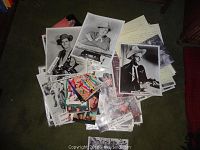 Image showing a pile of black and white 8x10 photos and some small color front cards on a floor with some handwritten papers visible