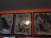 Three framed black and white photos of western stars and their horses hung on an orange wall: Gene Autry & Champion, Roy Rogers & Trigger, Charles Starrett & Raider.