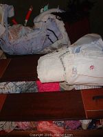 Drawers containing folded embroidered linens and aprons with lace and floral designs