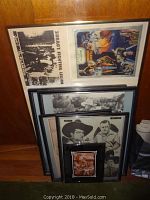 Vintage framed western art prints and photos stacked against wall, includes Zorro's Fighting Legion poster and cowboy images