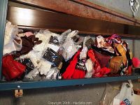 Wide view of assorted scarves and gloves piled in a box, showing variety of colors and materials.