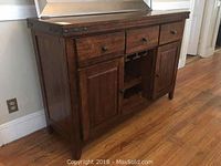 Full view of solid wood mission style sideboard with 3 drawers, 2 cabinet doors, and metal hardware on wooden floor