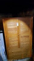 Closed wooden armoire with two paneled doors and two drawers at bottom